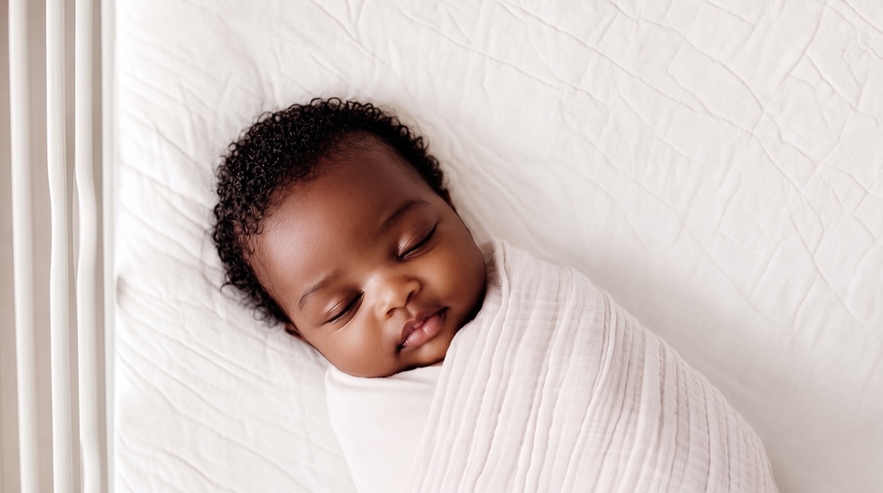A sleeping newborn wrapped safely in a white blanket